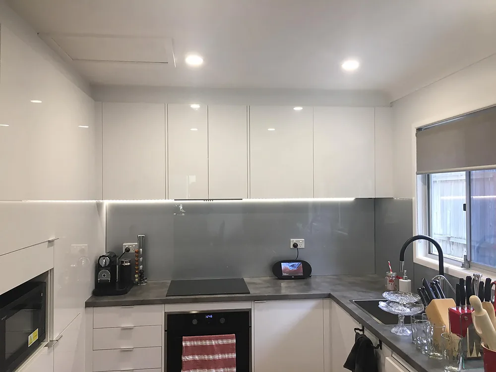Renovated white kitchen with LED downlights, strip lighting and a new oven