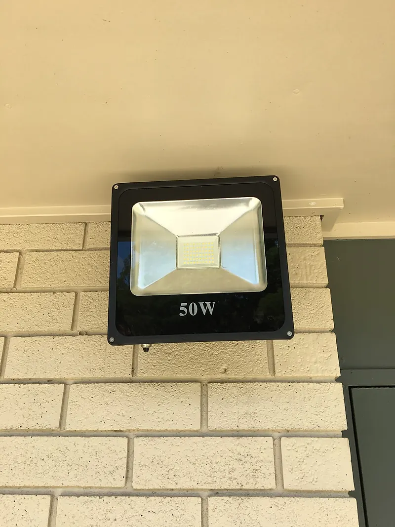 50 watt LED floodlight mounted under the eaves on a brick wall