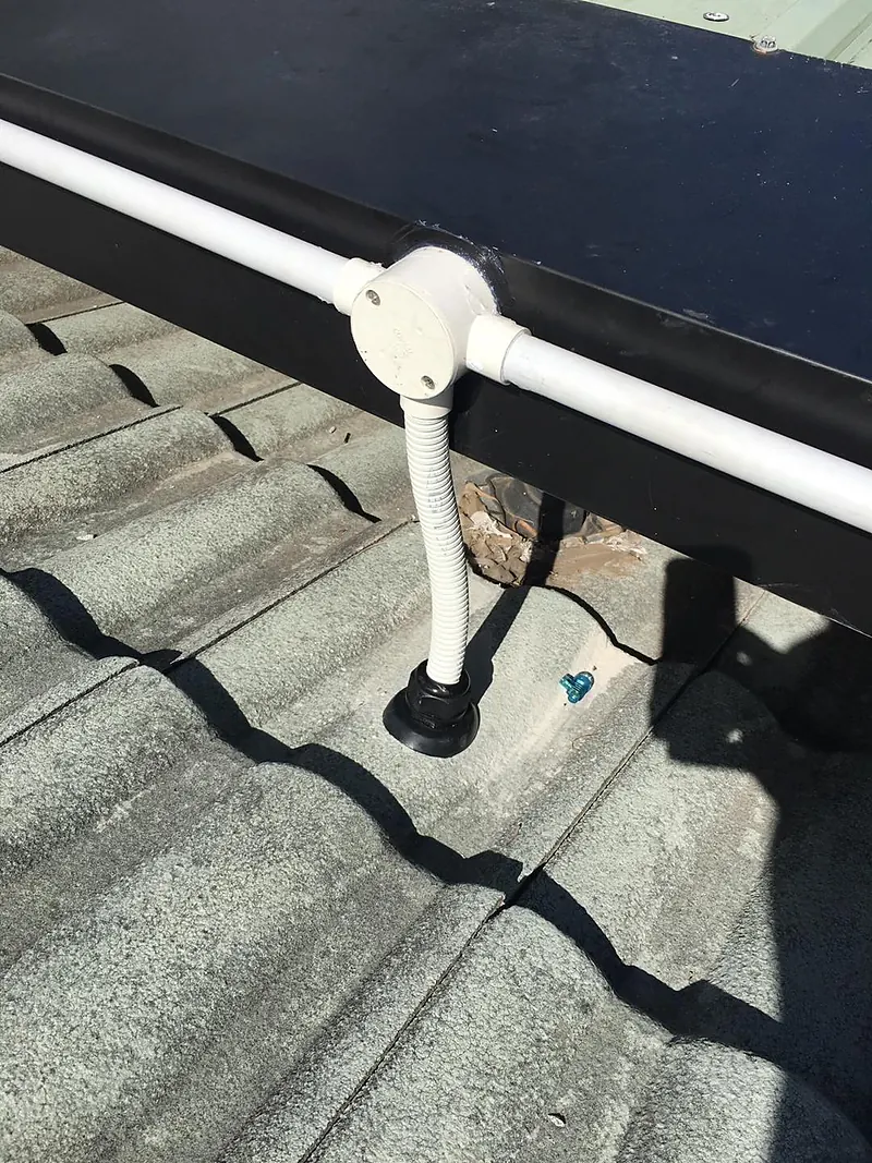 Conduit through a tiled roof with a sealed roof penetration